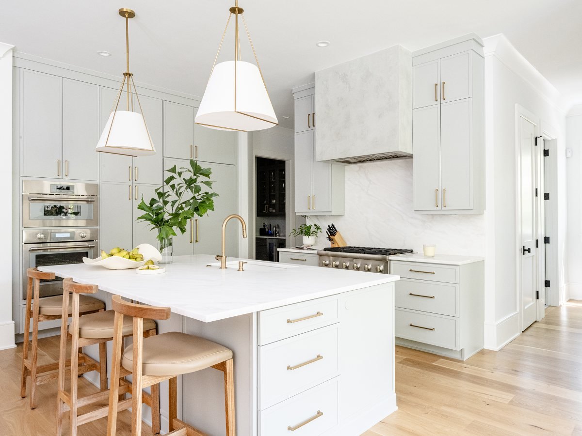 Kith Kitchens painted shaker kitchen with a slab marble backsplash, plaster hood and white oak stools — manufacturer photo