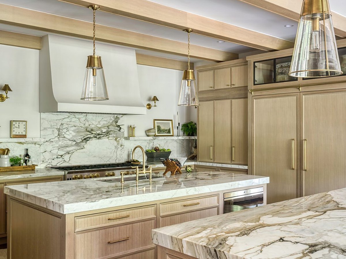 Plain & Fancy custom white oak kitchen with a bookmatched marble backsplash, plaster hood and brass pendants — manufacturer photo
