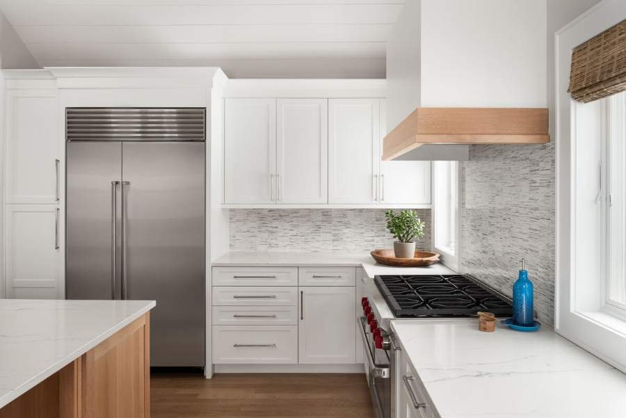 Plain & Fancy white shaker kitchen with a wood hood and marble-look counters — manufacturer photo