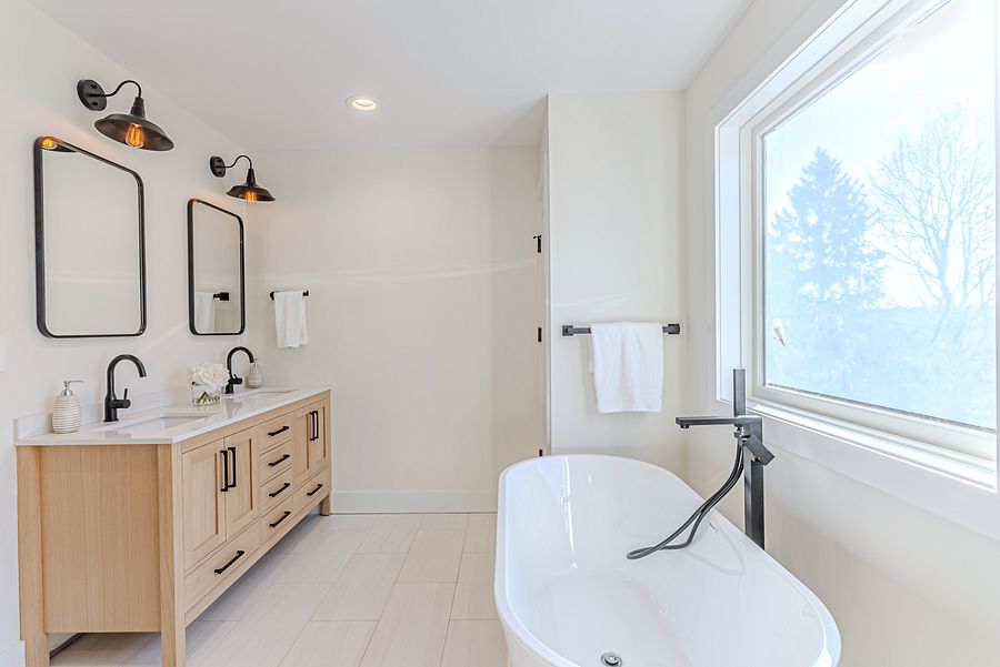 White-oak and navy bathroom vanities with a freestanding tub and black fixtures in Chatham, NJ