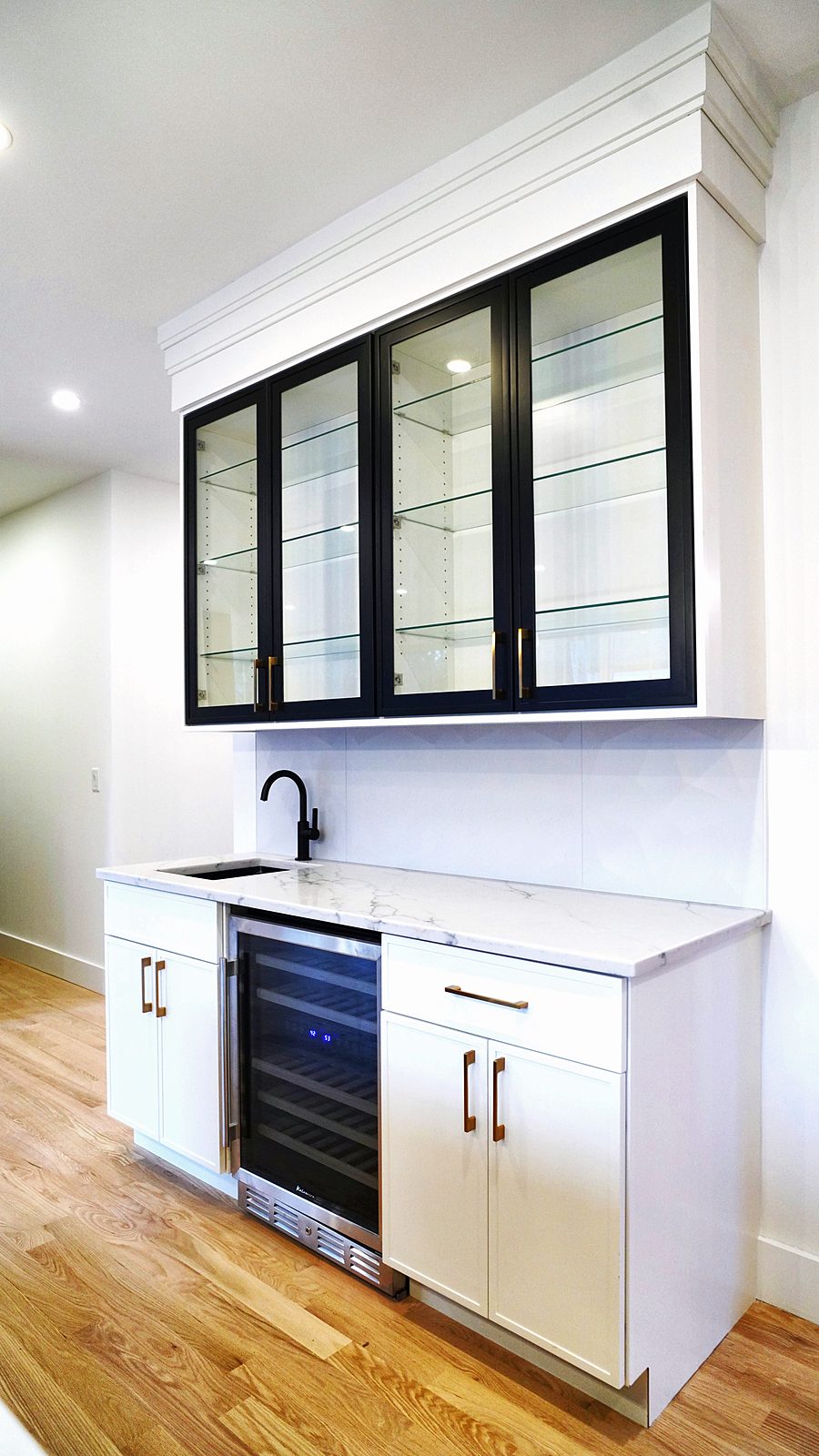 Bar wall with beverage center and black-framed glass uppers
