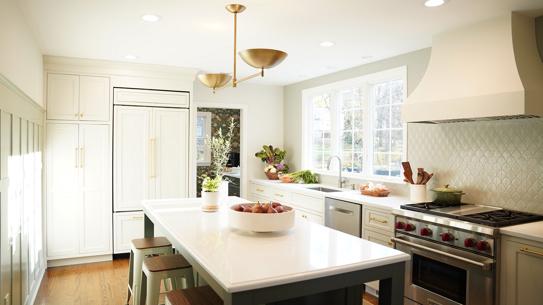 Cream inset kitchen with a deep green furniture-style island, a plaster-style hood and a pro-style range