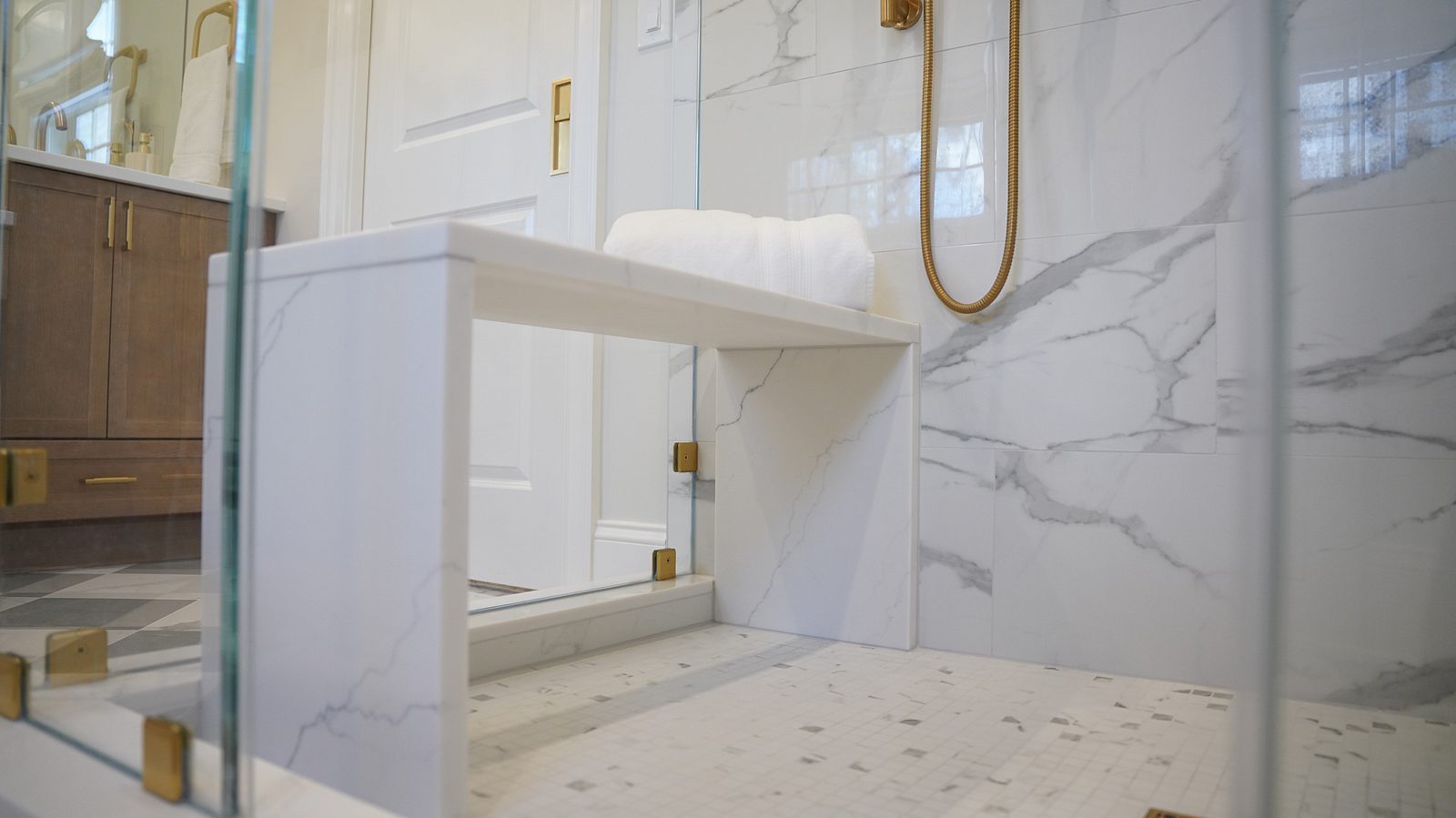 Marble-look porcelain shower with a bench and brass fixtures