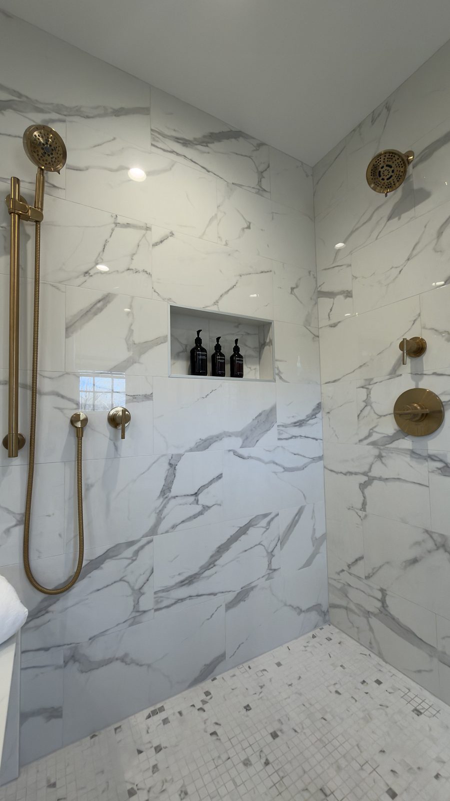 Shower niche and brass hand shower in the marble-look porcelain