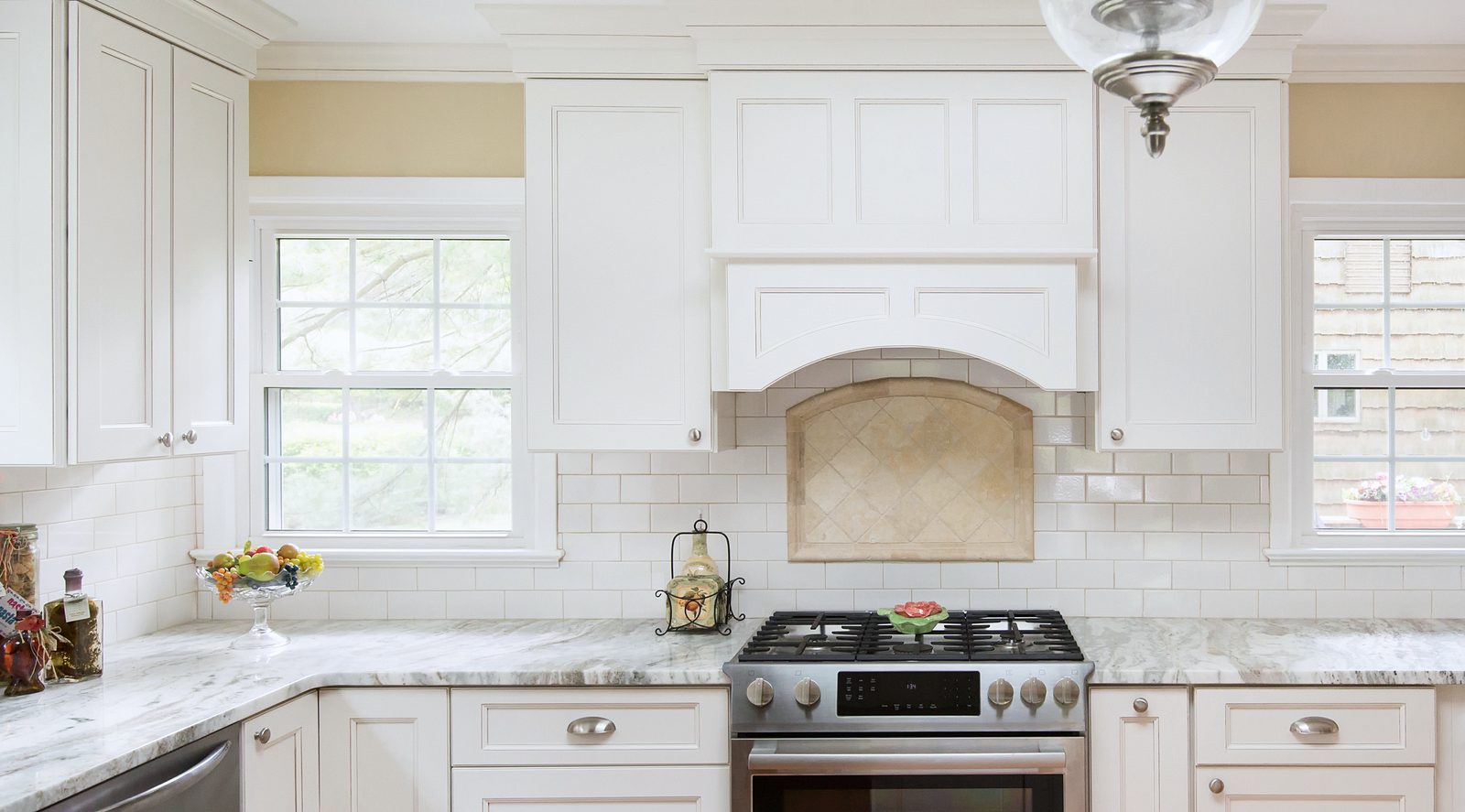 Arched valance hood over a diamond-set tile panel — Fabuwood Fusion in Blanc with a granite island and an arched hood