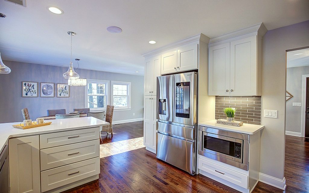 Gray subway-tile backsplash, stainless chimney hood — FGM Mercury White kitchen with gray subway tile and an open dining room
