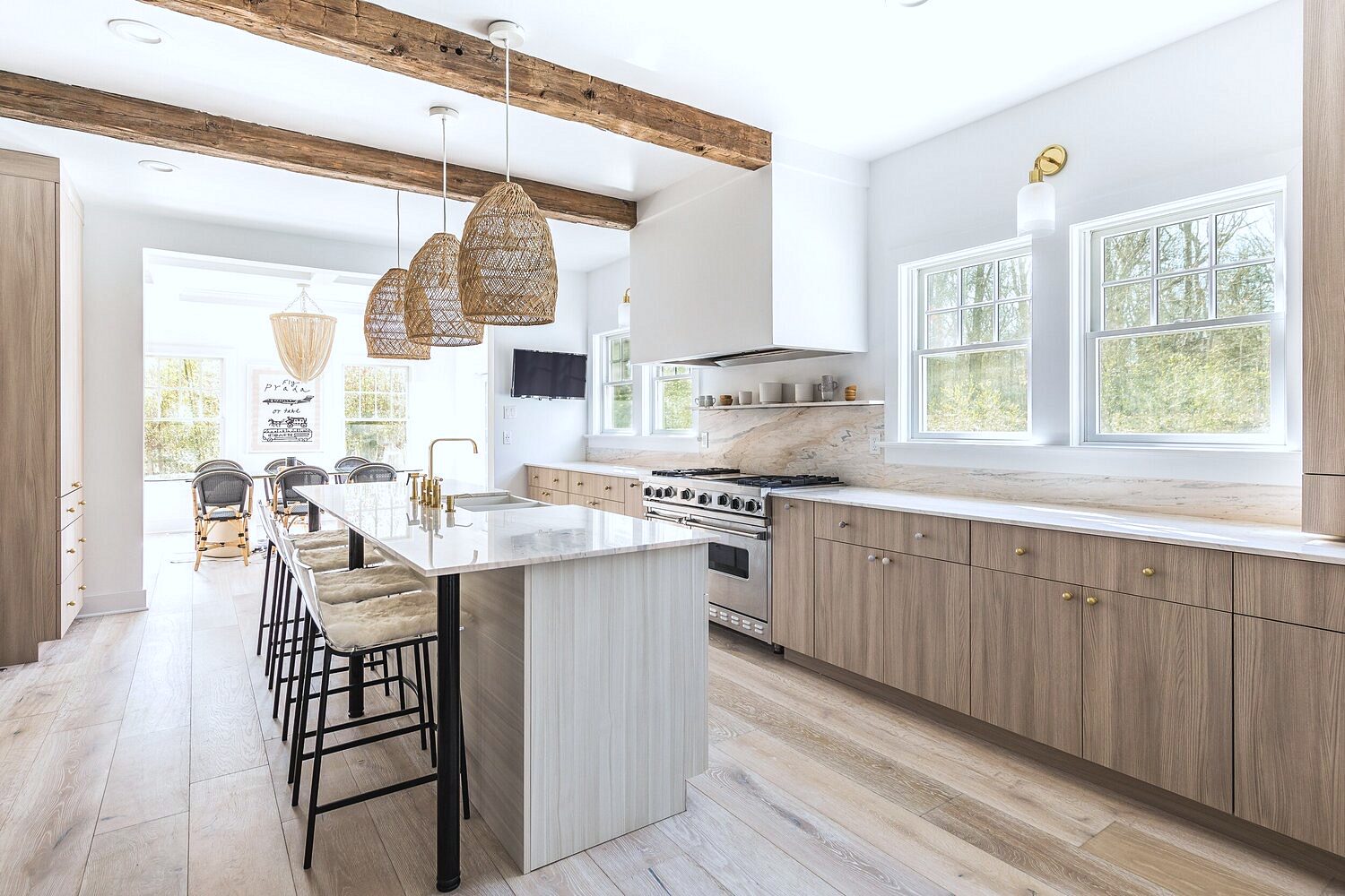 Light wood-grain flat-panel doors — Light wood slab kitchen with a white waterfall island and rattan pendants