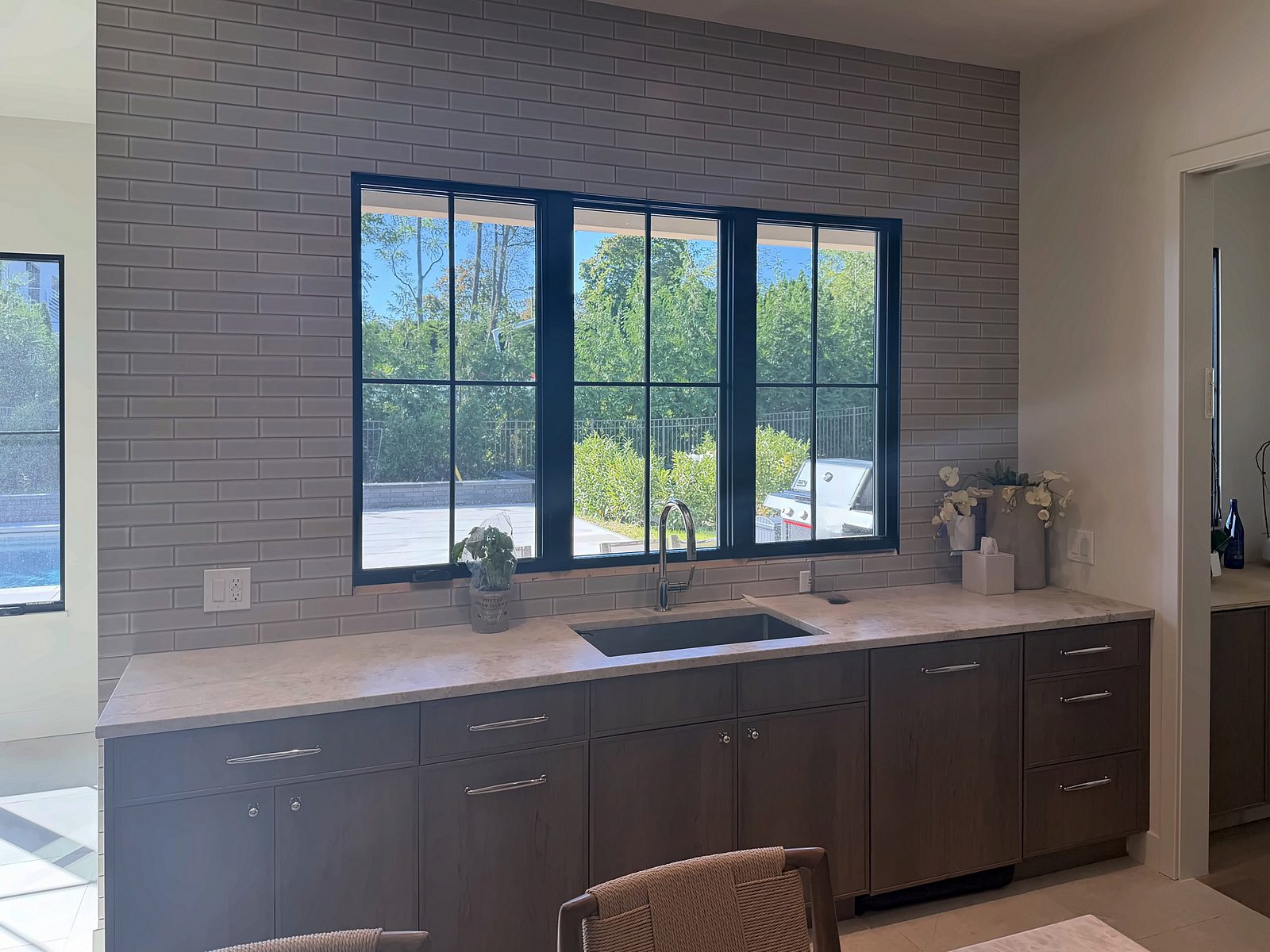 Sink wall with glazed subway tile, black-framed windows and the pot filler