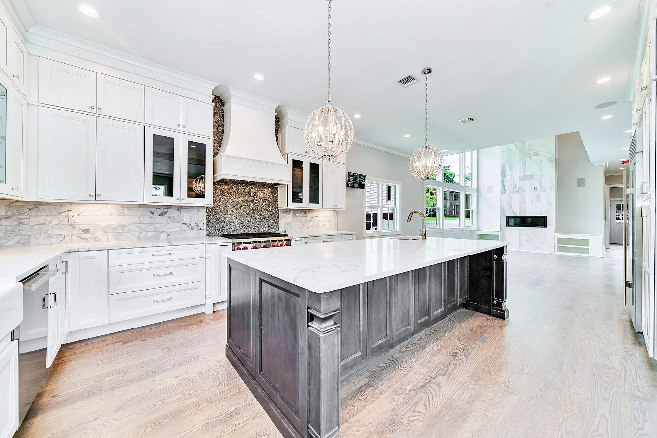 White shaker kitchen with a long charcoal island in a two-story great room in Paramus, NJ