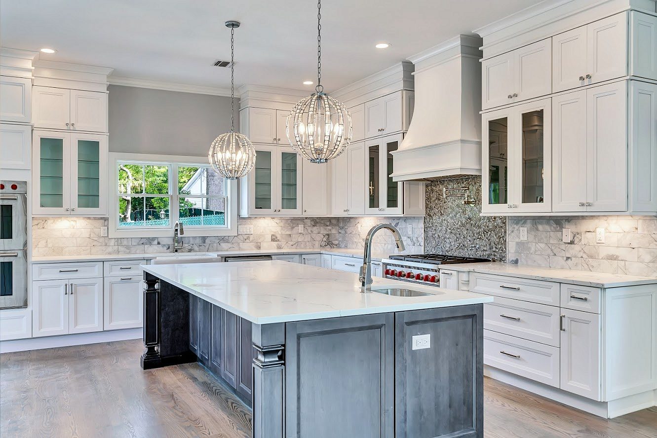 Long charcoal island with a white quartz top — White shaker kitchen with a long charcoal island in a two-story great room