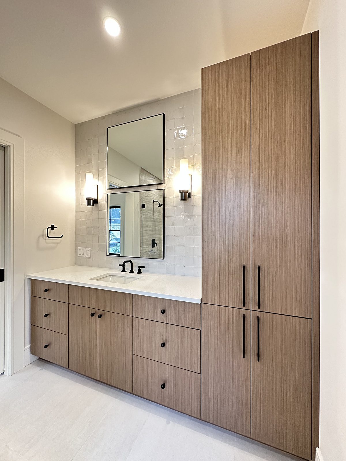 Wood-grain vanity and matching linen tower with matte black fittings