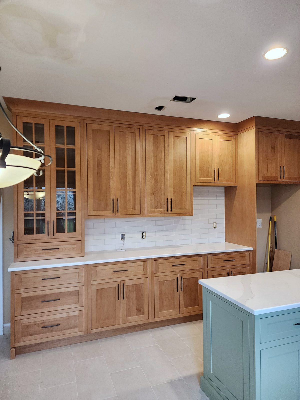 Sage green island with a white quartz top — Shiloh Hanover kitchen in a light brown stain with a green island
