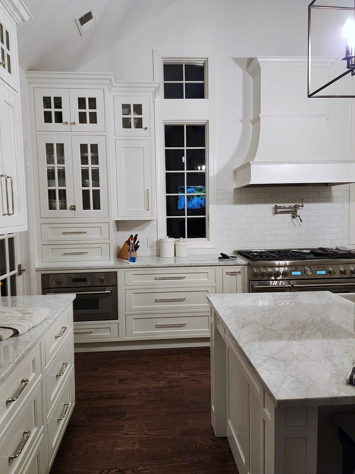 Bar with a beverage fridge and mirrored arabesque tile — Shiloh Heritage beaded-inset kitchen under a vaulted ceiling with a curved hood