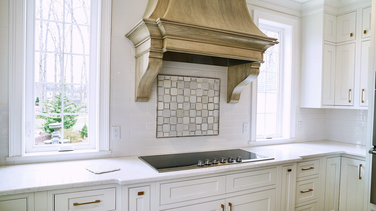 Carved wood hood over the marble mosaic backsplash