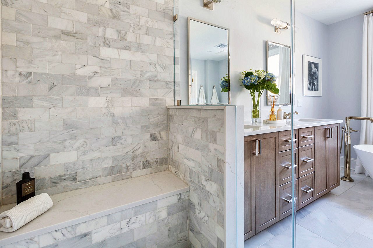 Marble shower bench beside the walnut vanity