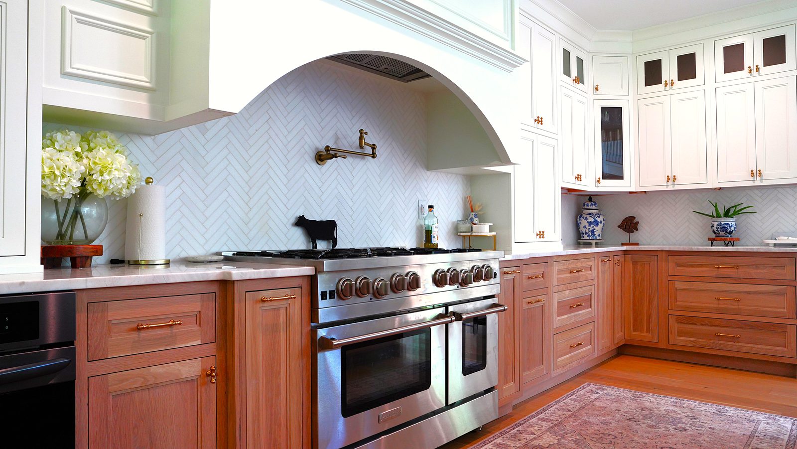 Pro-style range inside the arched hood with herringbone tile and a brass pot filler