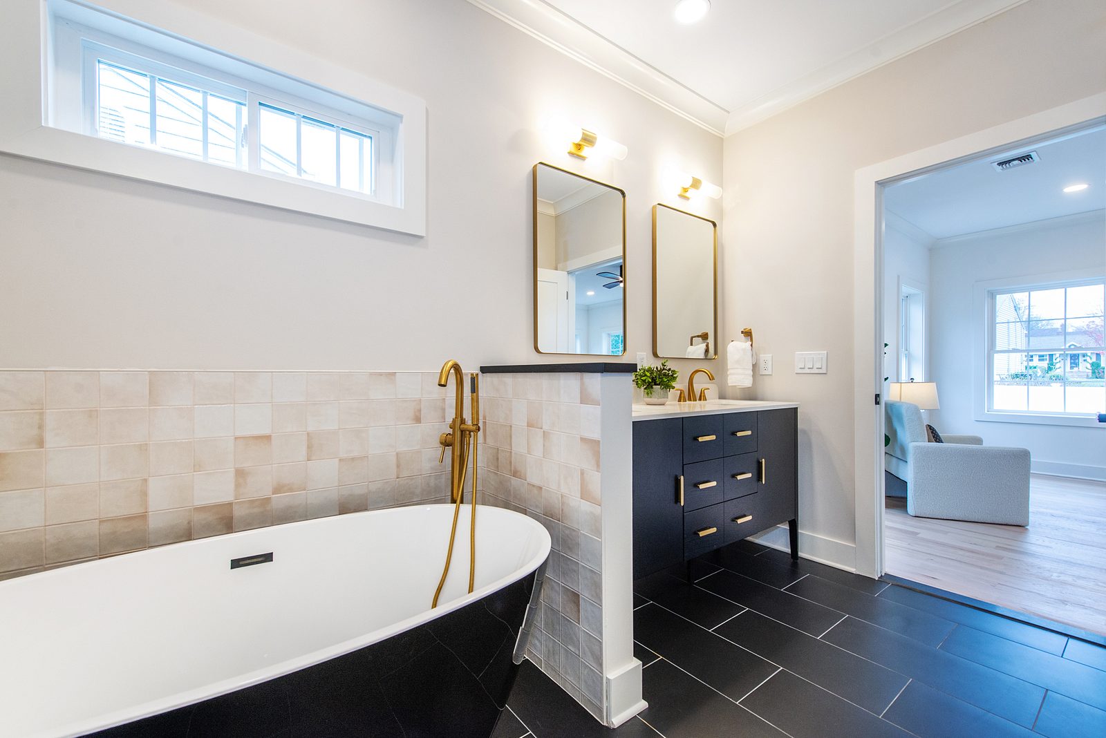 Black freestanding tub beside the black vanity against a zellige-look wall