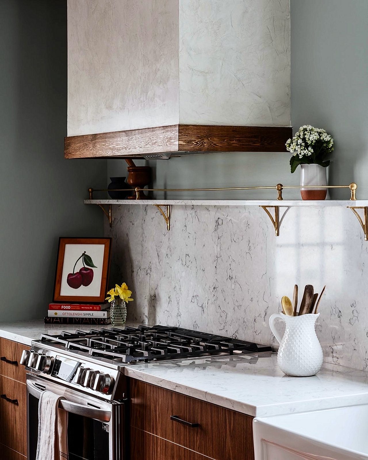 Walnut-grain flat-panel base cabinets, no uppers — Walnut slab kitchen with marble-look quartz, a farmhouse sink and brass