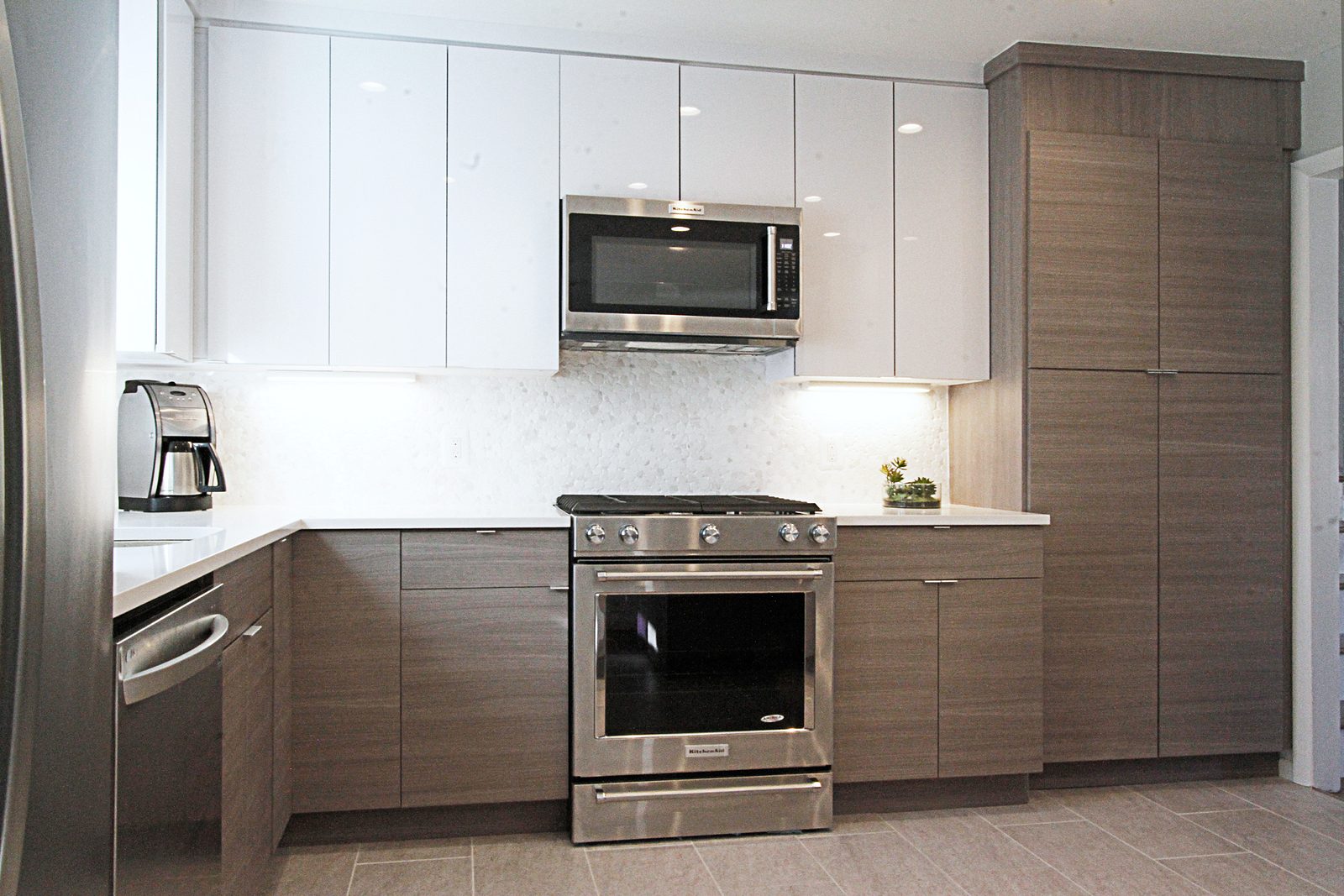 White quartz counters, glass-tile backsplash — White high-gloss and wood-grain slab kitchen