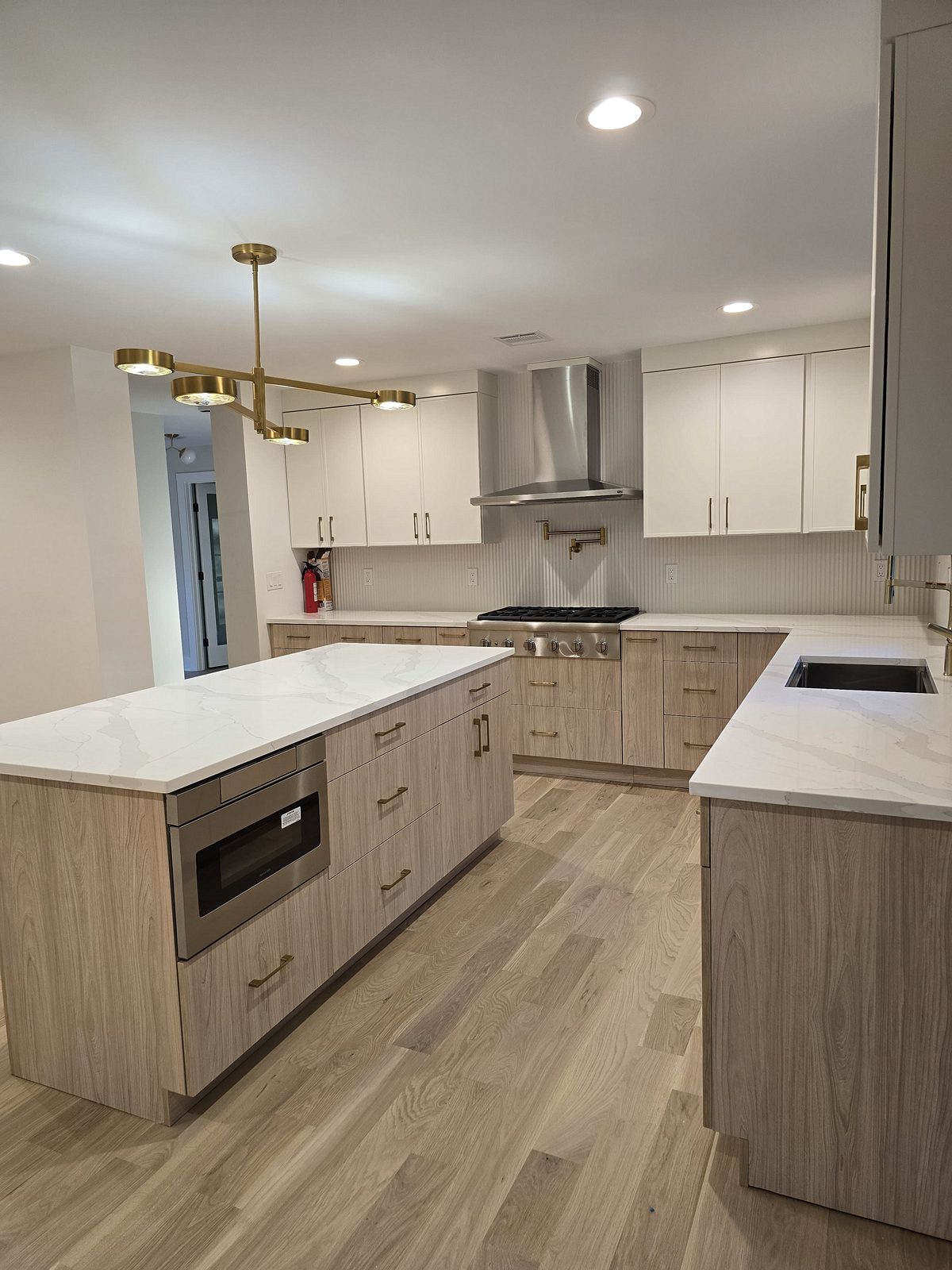 Cooktop under the stainless chimney hood between black-framed windows