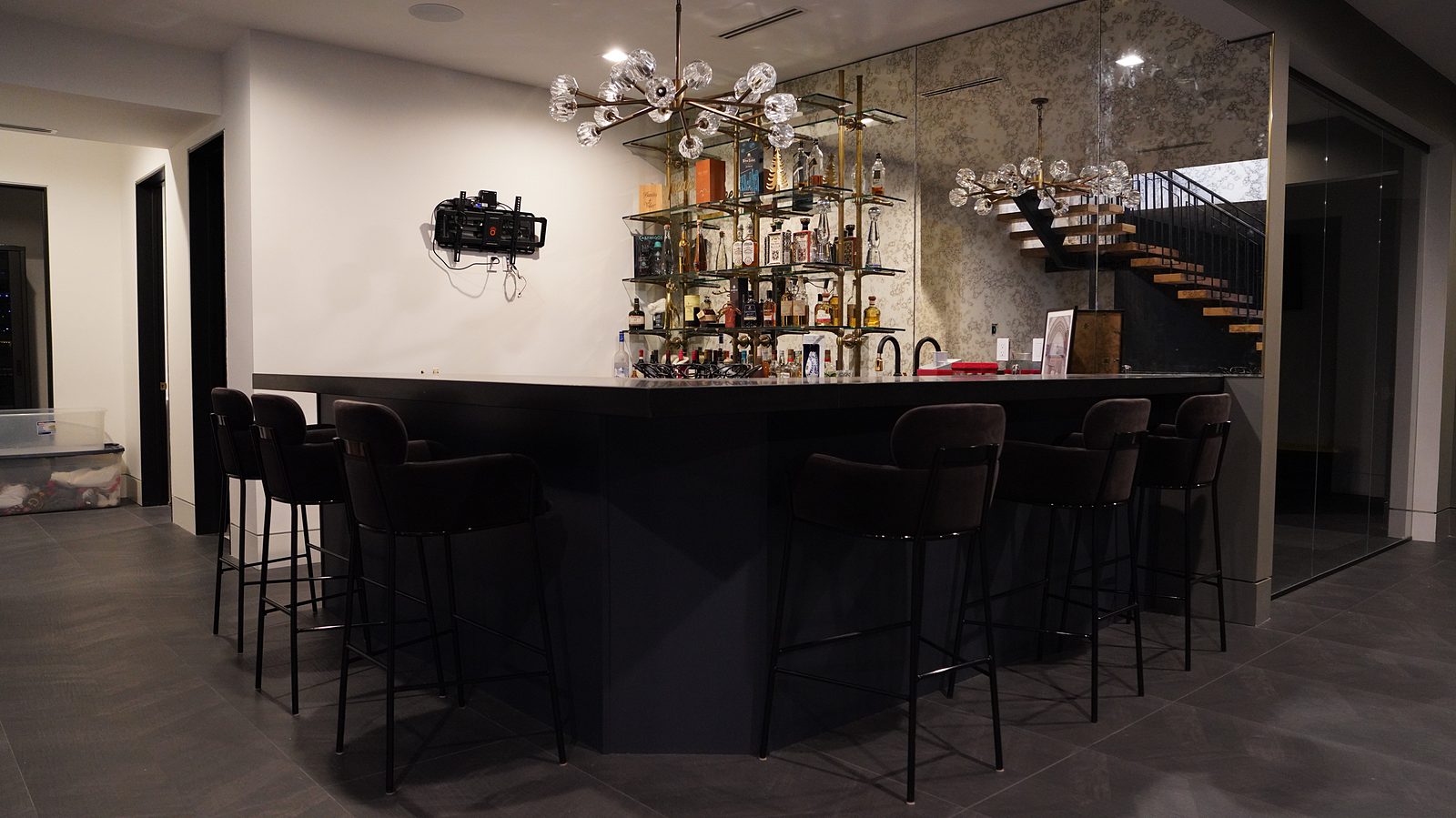 Black basement bar with black stools and a mirrored back bar