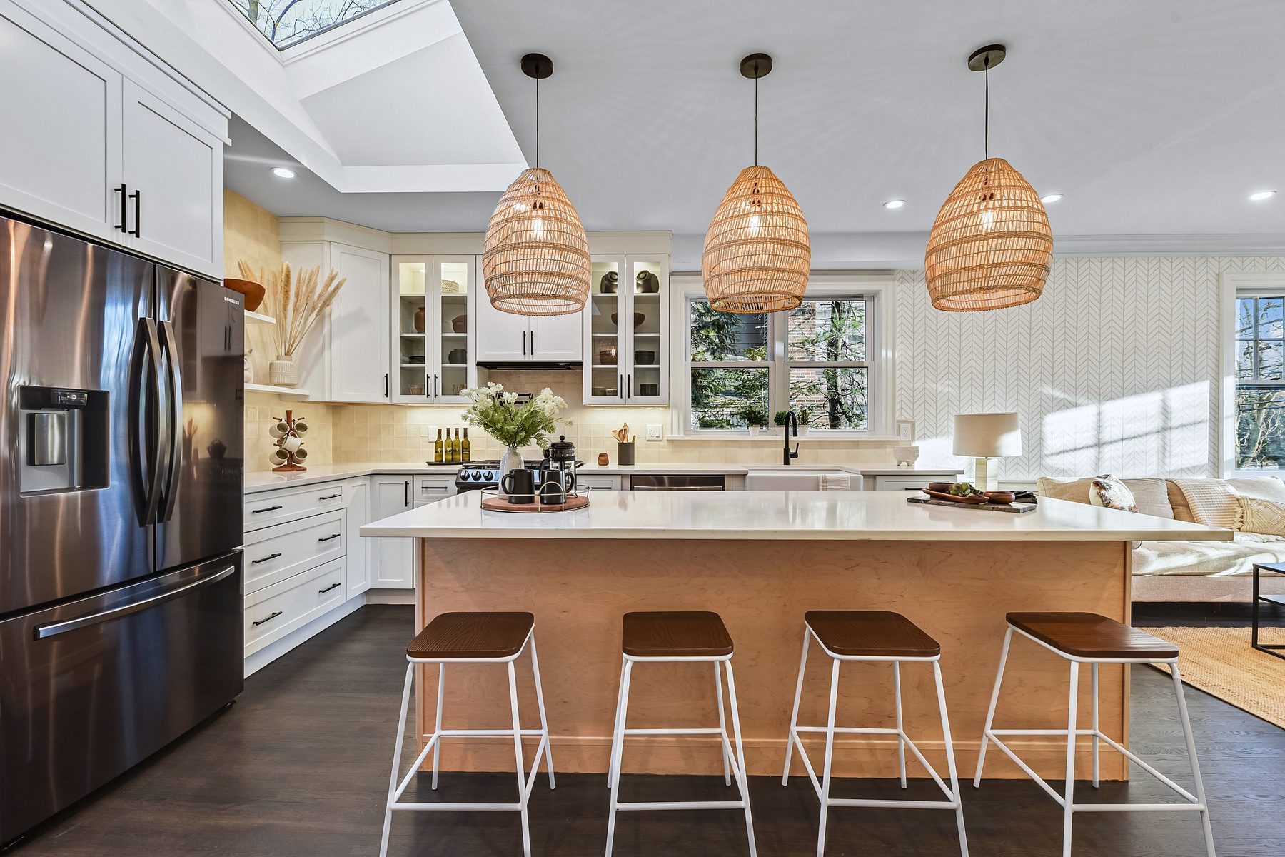 White shaker kitchen with a natural wood island and rattan pendants