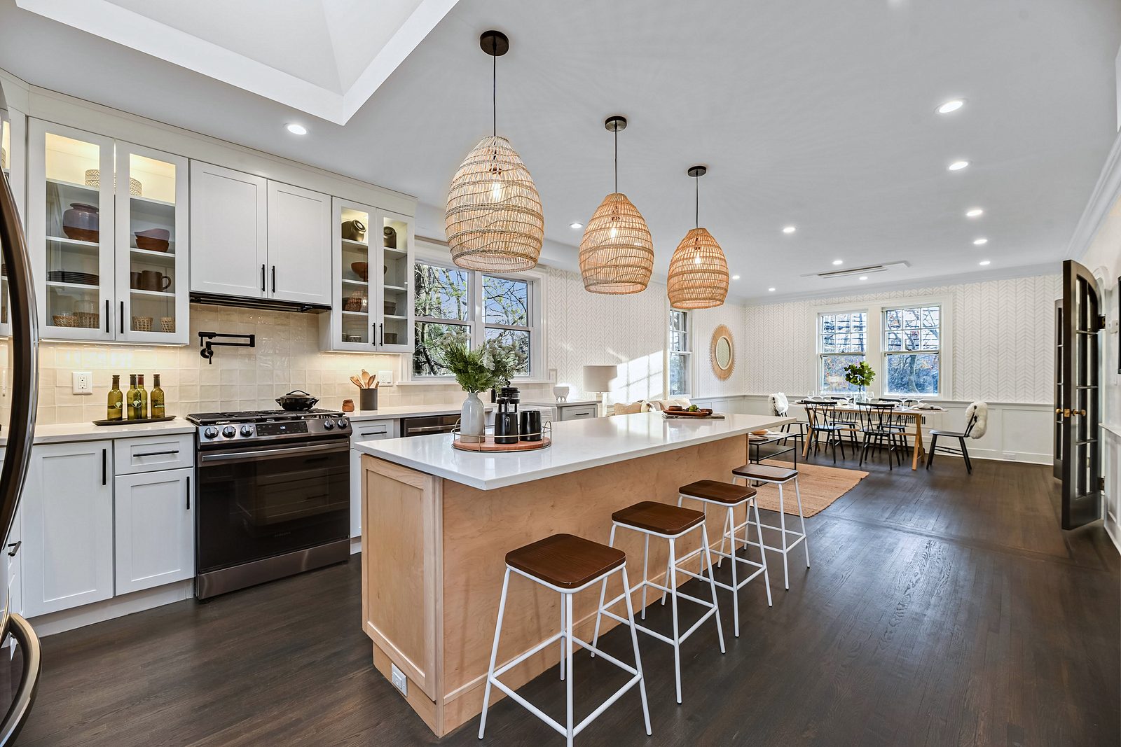 Natural wood island with seating for four — White shaker kitchen with a natural wood island and rattan pendants