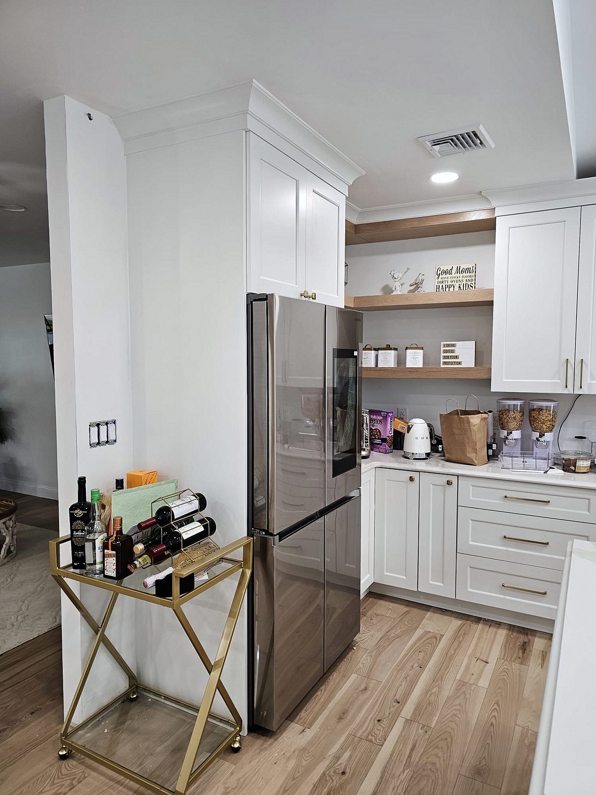 Natural wood corner shelves and hood band — White shaker kitchen with X-mullion glass uppers and a stained wood island on turned legs