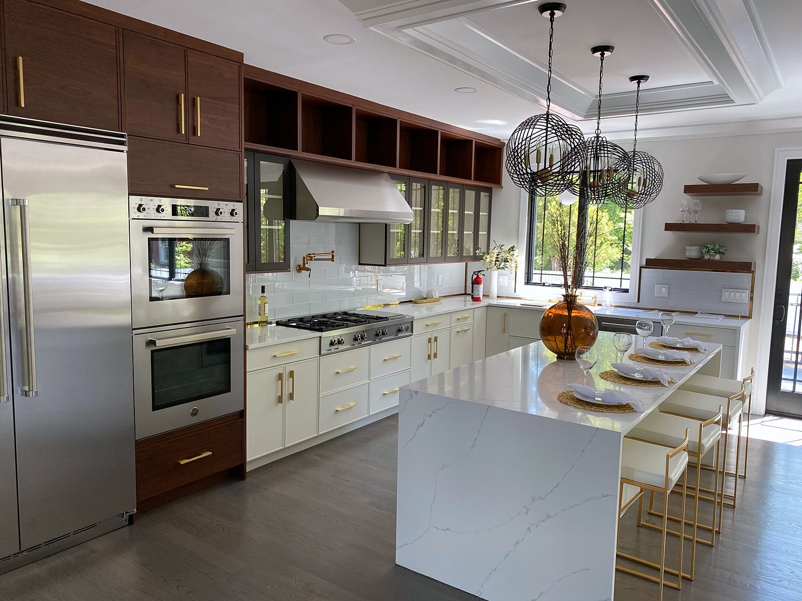 White quartz waterfall island with gold stools — White slab and walnut kitchen with a waterfall island