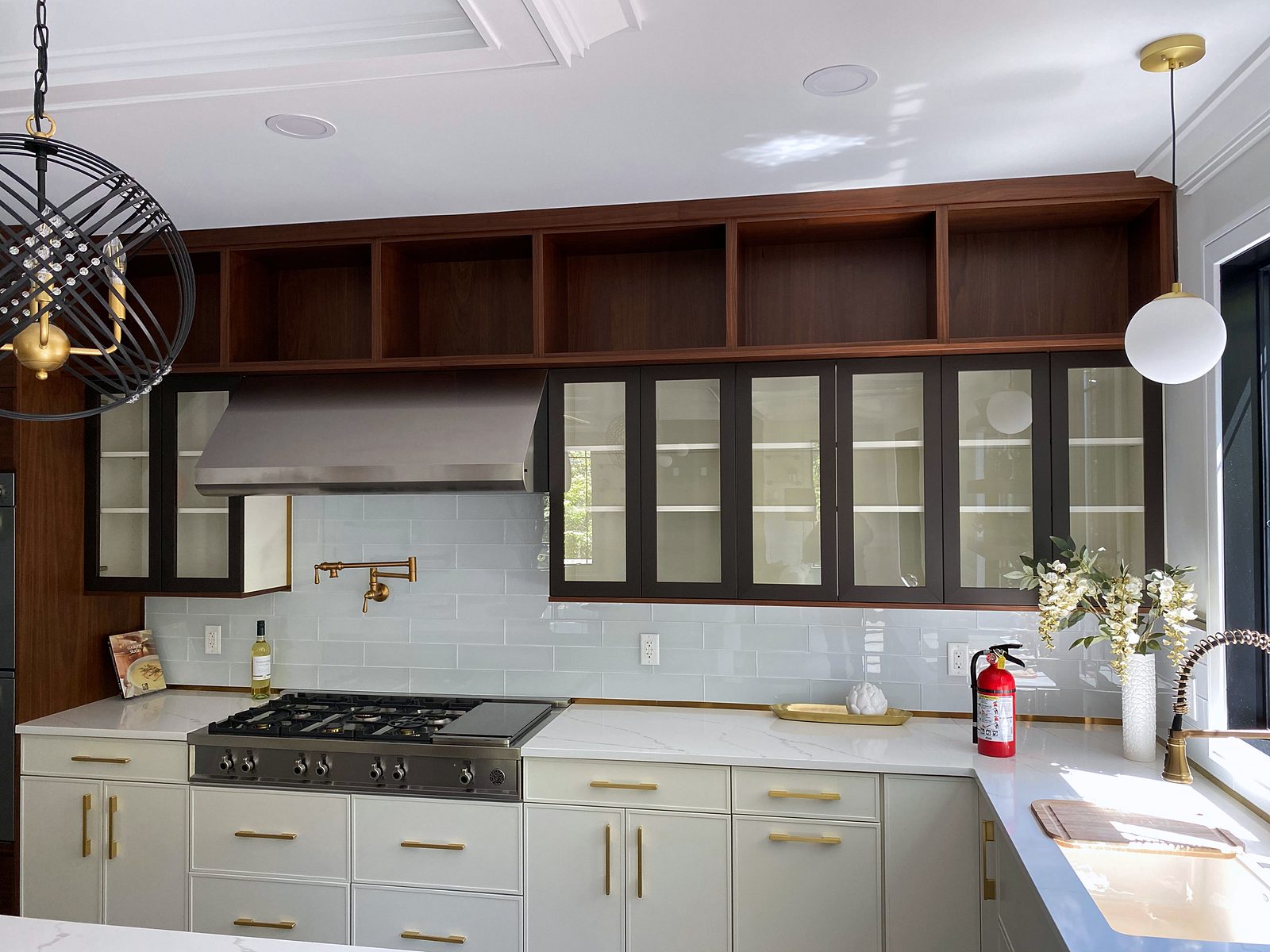Walnut floating shelves, pot filler — White slab and walnut kitchen with a waterfall island